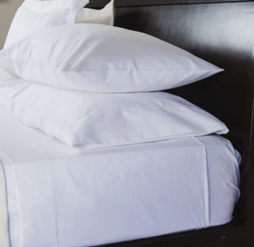 Sábana ajustable blanca de algodón egipcio enrollada en cama-