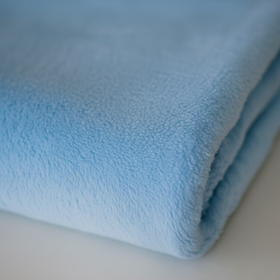 Frazada polar infantil celeste enrollada mostrando su textura suave-