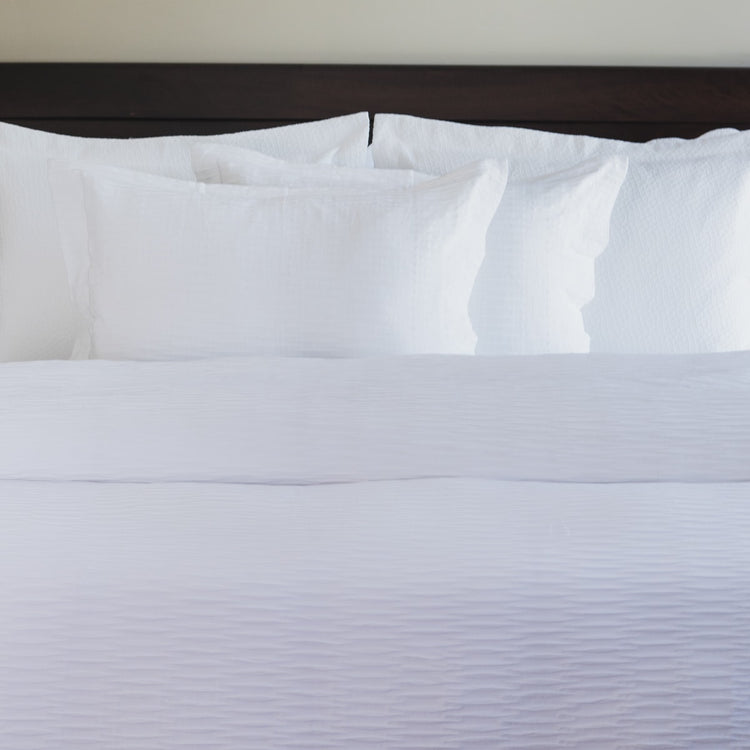 Funda edredón ondas natural cama con almohadas blancas y cabecera oscura-natural