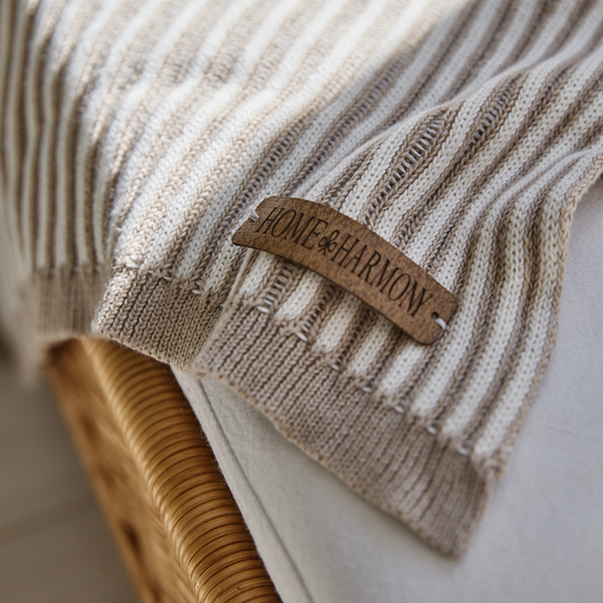 Manta beige con etiqueta de cuero Home & Harmony en silla-beige