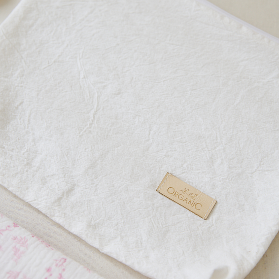 Manta blanca orgánica con etiqueta dorada y detalle rosa-rosa