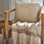 
                    
                      Almohada beige texturizada sobre silla madera con manta a cuadros-beige
                    
                  