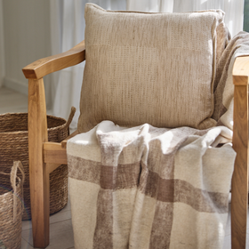Almohada beige texturizada sobre silla madera con manta a cuadros-beige