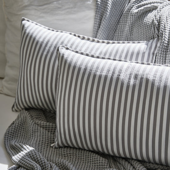 Almohada Capri gris con rayas blancas sobre manta textil-gris