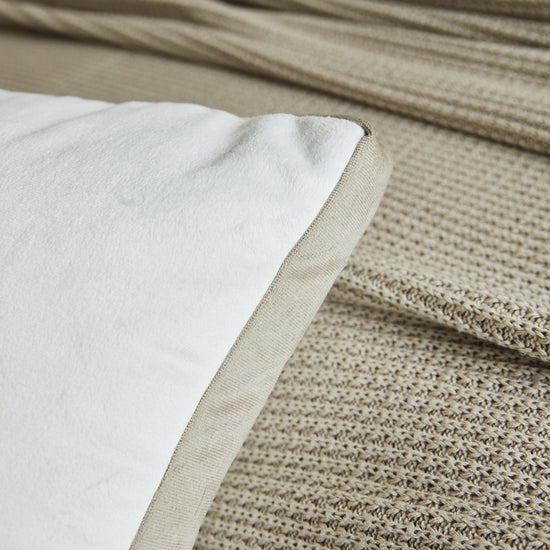 Almohada beige con funda blanca sobre piso de madera-beige