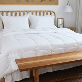 Cama con edredón blanco antibacterial y almohadas sobre cabecera de ratán-blanco