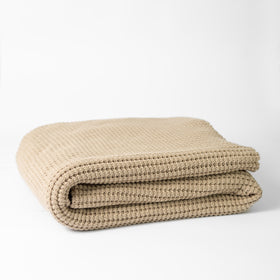 Manta de lana beige Roma doblada sobre fondo blanco-beige