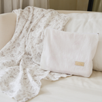 
                    
                      Set de nacimiento con almohada blanca y manta floral beige en cama-
                    
                  
