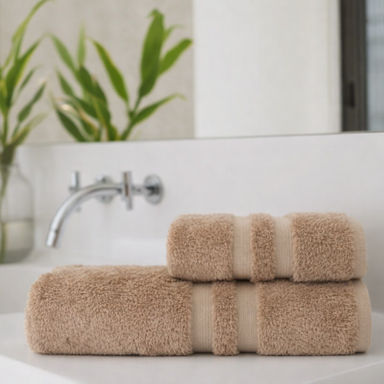 Set de toallas beige enrolladas con banda decorativa en baño moderno-