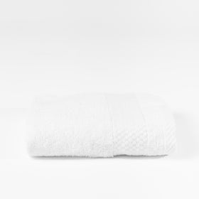 Toalla blanca textura honeycomb doblada sobre fondo gris-blanco