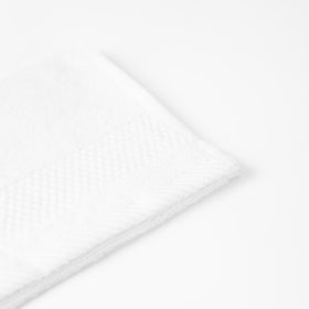 Toalla blanca con textura honeycomb doblada sobre fondo blanco-blanco