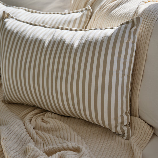 Almohada Capri beige a rayas en cama con textura de lino-beige