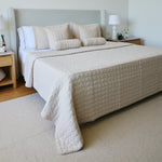 
                    
                      Cubrecama acolchado beige sobre cama con almohadas decorativas-beige
                    
                  