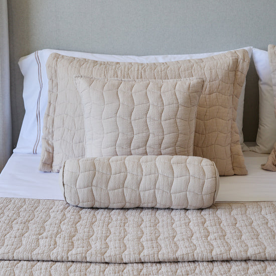 Cubrecama beige Nottingham con almohadas y cojín decorativo en cama-beige