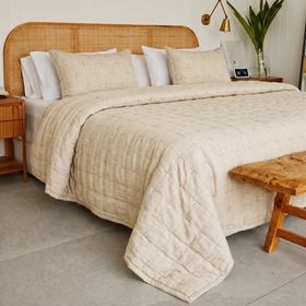 Cubrecama California beige con patrón de cruces en cama de madera-gris