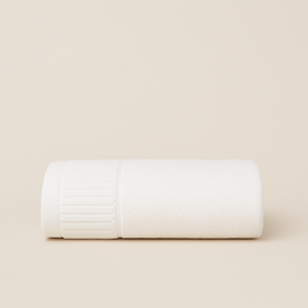 Toalla blanca enrollada sobre fondo beige claro-