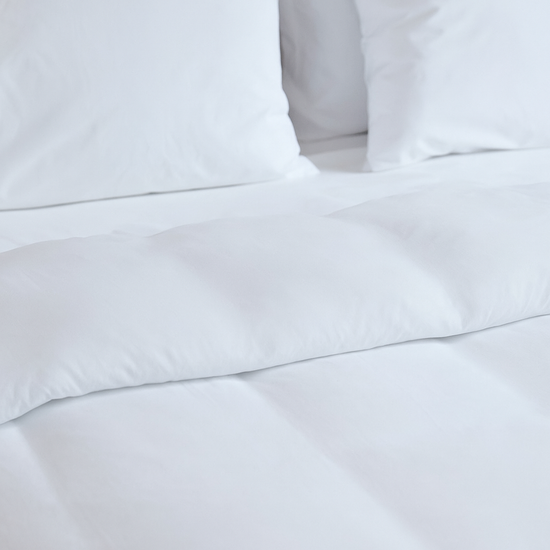 Almohada blanca sobre sábanas blancas de cama, vista de cerca-