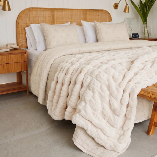 Cubrecama California beige con patrón quilted sobre cama con cabecera de ratán-beige