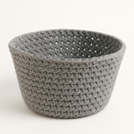 
                    
                      Cesta tejida gris claro con patrón de crochet y abertura superior-
                    
                  