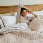 
                    
                      Mujer en cama con sábanas de algodón egipcio blanco y beige-
                    
                  