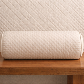 Almohada cilíndrica beige con patrón acolchado sobre superficie de madera-beige