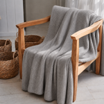 
                    
                      Manta de lana tipo angora color gris sobre silla de madera kiri-gris
                    
                  