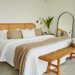 
                    
                      Cama con cubrecama beige texturizado sobre sábanas blancas y almohadas decorativas-
                    
                  
