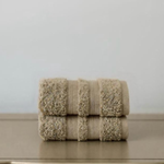 
                    
                      Dos toallas de baño beige texturizadas apiladas sobre superficie blanca-
                    
                  