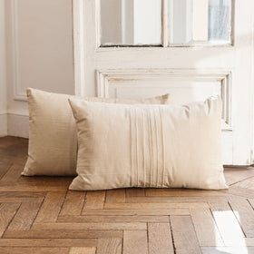 Dos almohadas beige de lino sobre suelo de madera en interior minimalista-natural