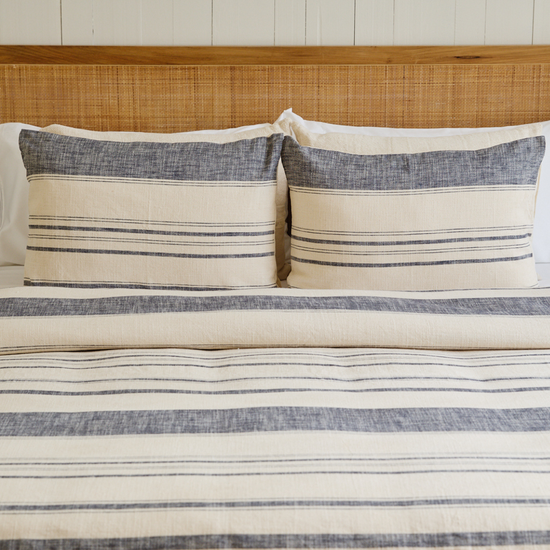 Cama con funda de edredón azul y blanco a rayas con dos cojines-azul