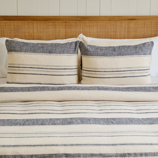 Cama con funda de edredón azul a rayas y dos almohadas decorativas-azul