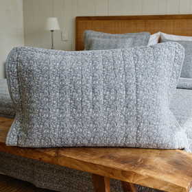 Funda de almohada Leicester gris con textura acolchada sobre banco de madera-gris