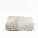 
                    
                      Toalla beige doblada con textura de algodón suave y bordes decorativos-
                    
                  