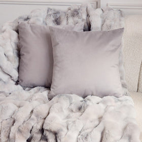 Almohadas grises y blancas sobre manta de peluche suave-