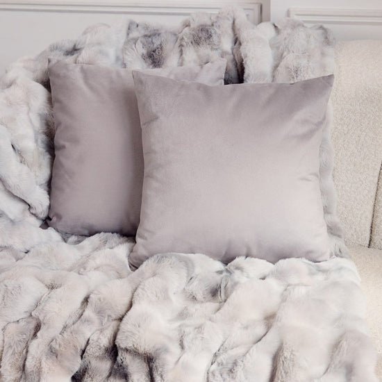 Almohadas grises y blancas sobre manta de peluche suave-