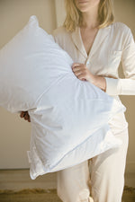 
                    
                      Mujer sostiene almohada blanca de hotel mostrando calidad y comodidad-
                    
                  