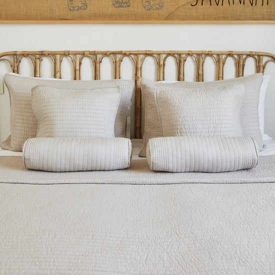 Cama con almohadas beige y cabecero de ratán natural-beige