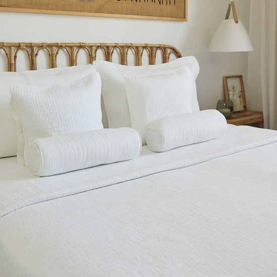 Cama con almohadas y cilindros de lino blanco natural decorativo-natural
