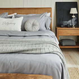 Almohada capitoné gris redonda sobre cama con sábanas grises-gris