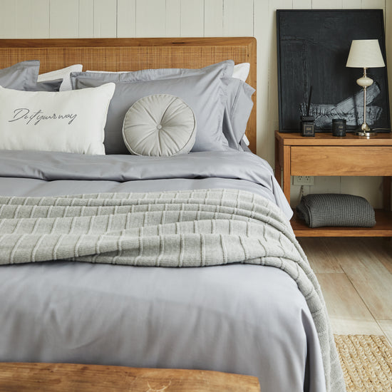 Almohada capitoné gris redonda sobre cama con sábanas grises-gris