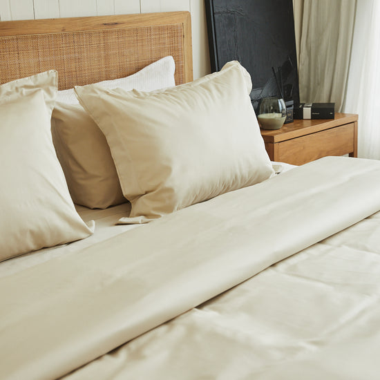 Cama con funda de edredón blanca de algodón bambú en dormitorio moderno-natural