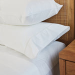 
                    
                      Dos fundas de almohada blancas con acabado vainilla sobre cama de madera-blanco
                    
                  