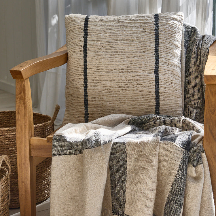 Almohada beige con rayas negras sobre silla de madera-azul