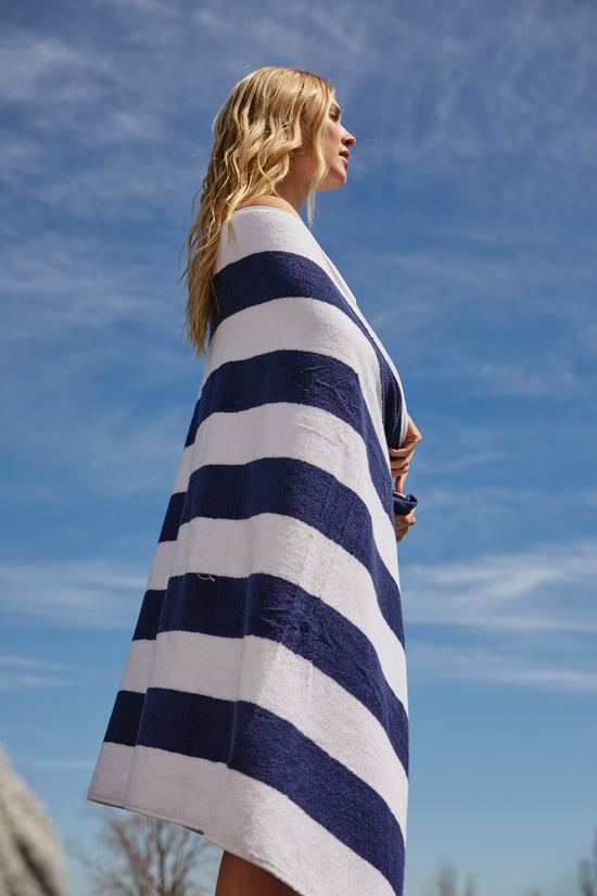 Mujer envuelta en toalla de playa a rayas azul y blanco-azul