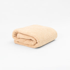 Manta corderito beige enrollada sobre fondo blanco-