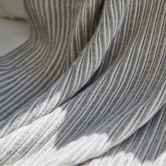 Manta gris con costillas verticales y pliegues suaves enrollada-gris