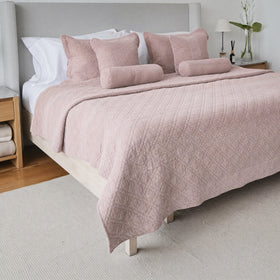 Cubrecama Manchester rosa con almohadas decorativas en cama gris-rosa