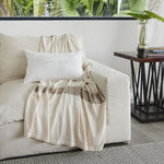 
                    
                      Manta Eugenia Rayas beige sobre sofá blanco junto a mesa-
                    
                  
