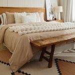 
                    
                      Manta blanca texturizada sobre cama beige con cabecero de ratán-natural
                    
                  