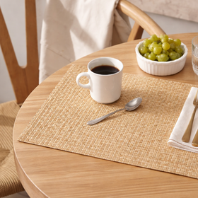 Mesa redonda de madera con individual tejido, café y uvas frescas-